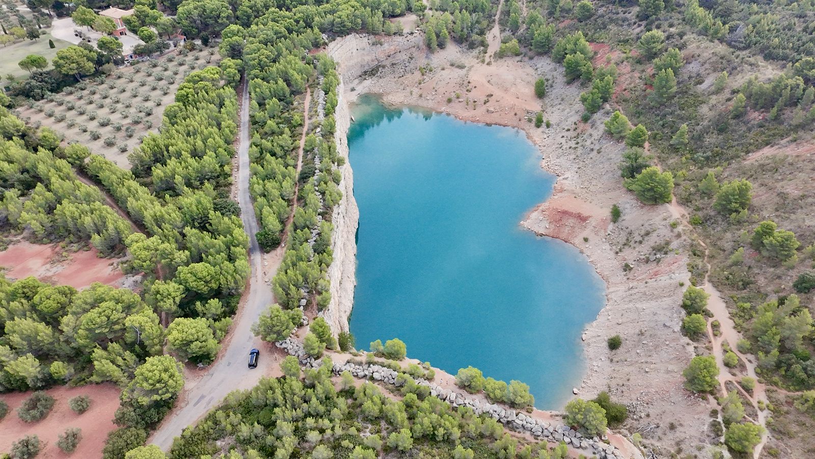 Vue aérienne d'un lac entouré de forêts et d'oliveraies, prise au drone